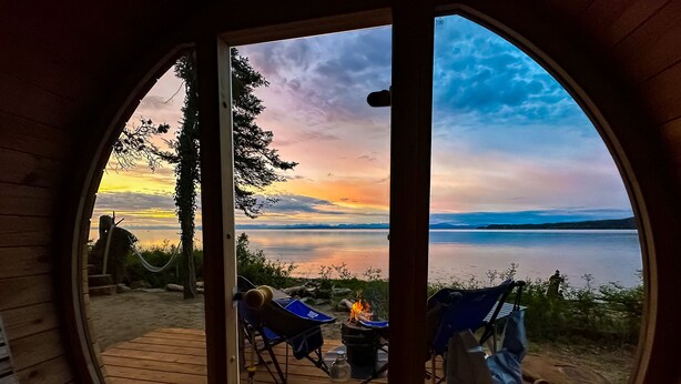 Una terraza de madera con vista a un lago y montañas al atardecer.