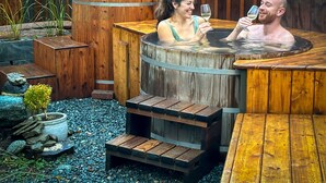 Un bain à remous avec des marches en bois et une clôture en bois rustique en arrière-plan.