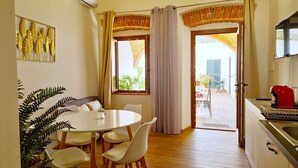A dining area with a round table and chairs, a potted plant, and a view of the outside through a doorway. - [Arcada 4] Apartment in the heart of Orosei (Orosei)