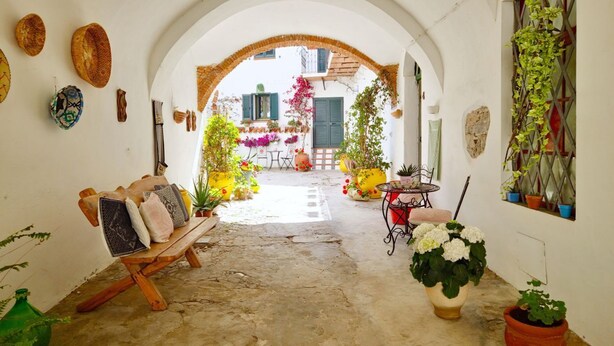 An interior courtyard with a wooden bench, potted plants, and a table with chairs. - [Arcada 4] Apartment in the heart of Orosei (Orosei)