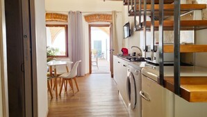 A kitchen with a washing machine, a dining area with chairs, and a staircase. - [Arcada 4] Apartment in the heart of Orosei (Orosei)