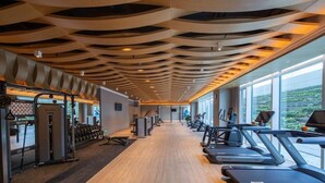 Une salle de sport équipée de tapis de course, d’appareils de musculation et dotée d’un plancher en bois.