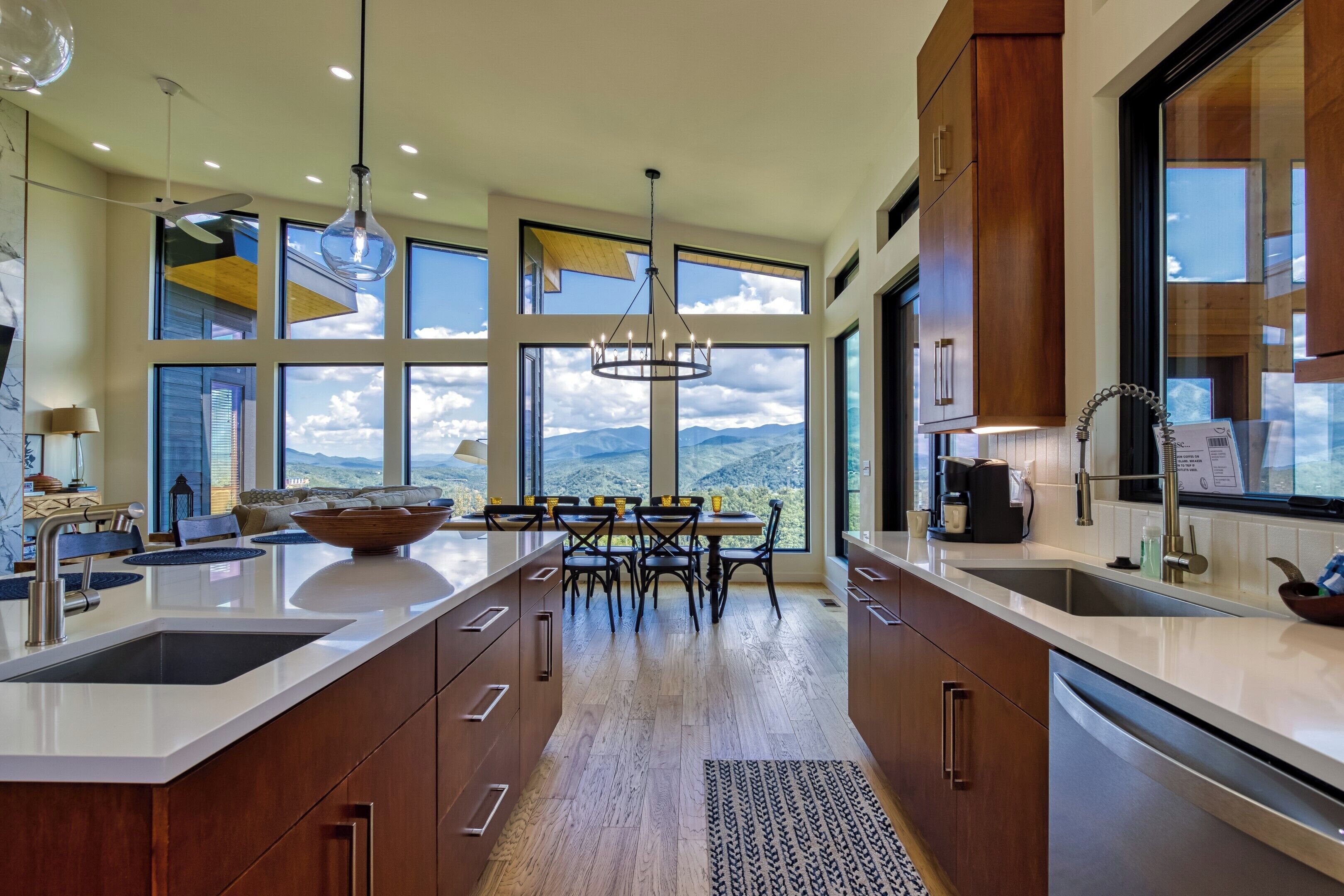 A modern kitchen with a large island, wooden cabinets, and a view of the mountains.