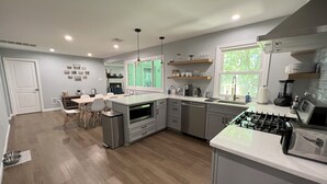 A modern kitchen with a central island, built-in appliances, and a dining area with a view of the outdoors. - Lakefront Retreat, Renovated, Pet Friendly, Close to All Area Attractions (Pocono Summit)