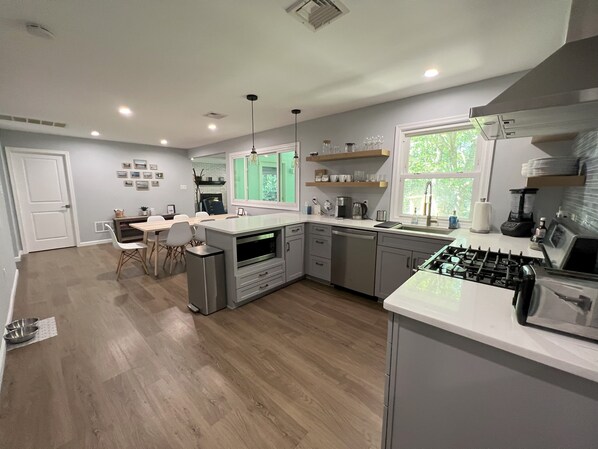 A modern kitchen with a central island, built-in appliances, and a dining area with a view of the outdoors. - Lakefront Retreat, Renovated, Pet Friendly, Close to All Area Attractions (Pocono Summit)
