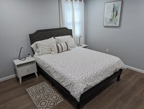 A bedroom with a bed, nightstands, a bedside table, a patterned rug, and a painting on the wall. - Lakefront Retreat, Renovated, Pet Friendly, Close to All Area Attractions (Pocono Summit)