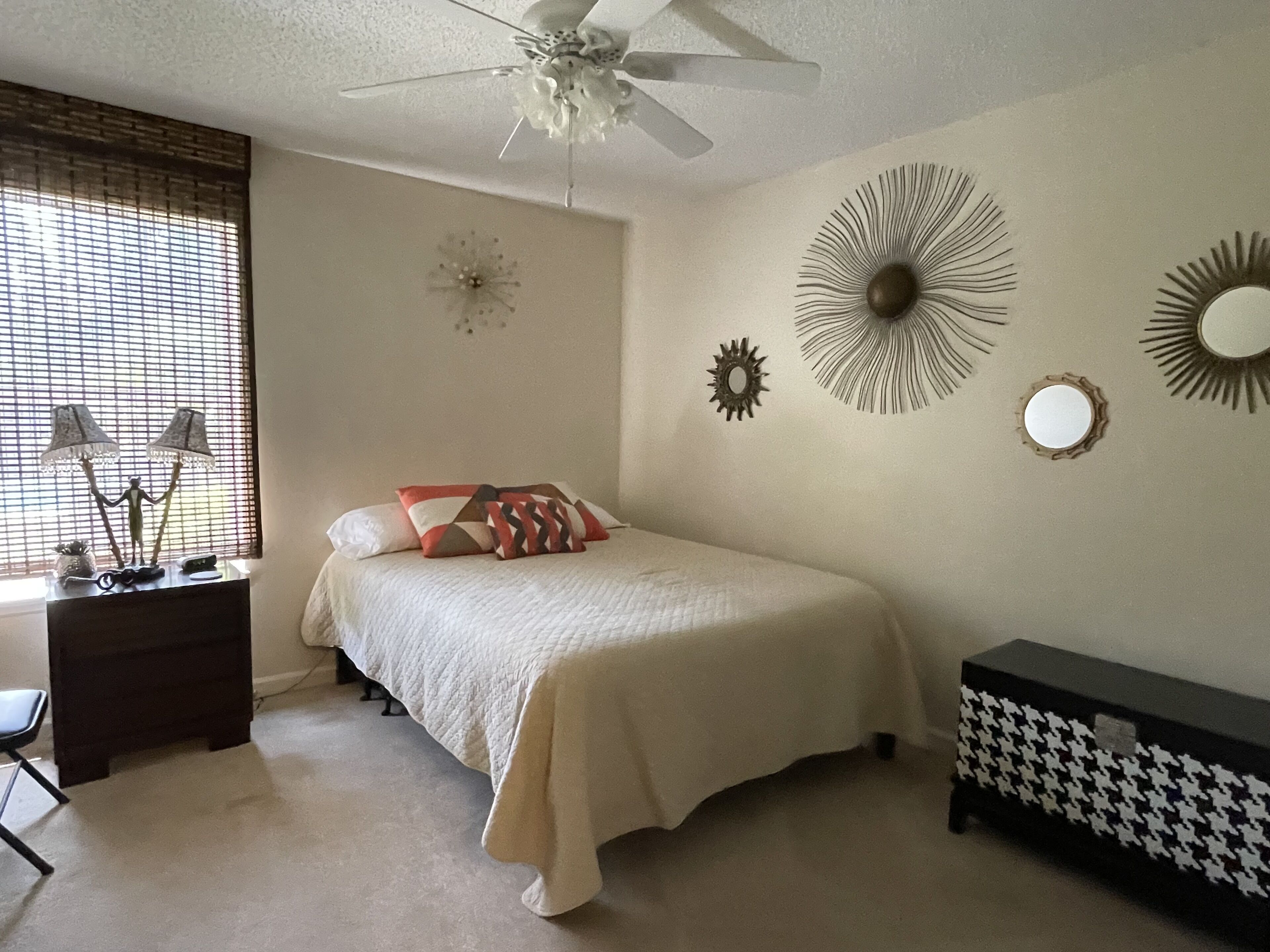 A bedroom with a bed, bedside tables, a desk, a chair, and decorative wall art.