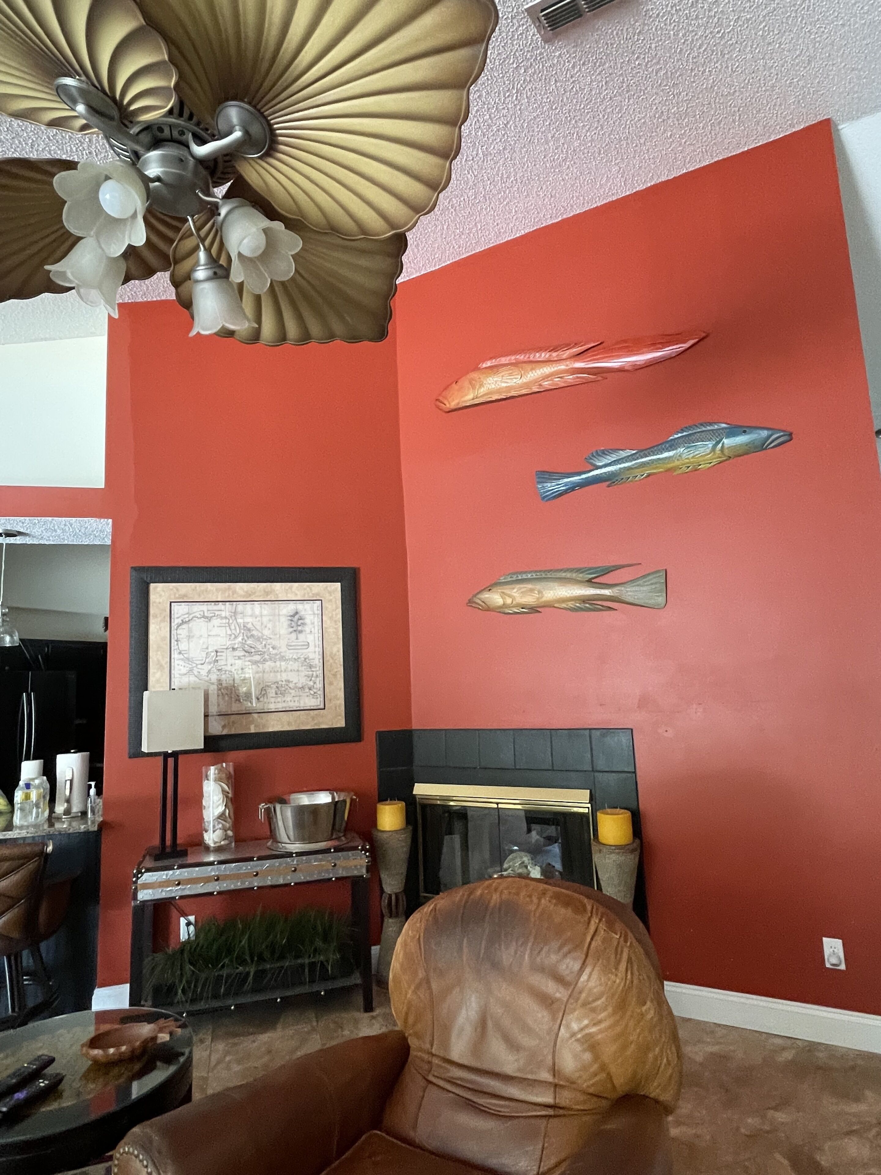 A living room with a red wall, a fireplace, and three fish wall art pieces.