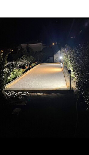Ein gut beleuchteter Weg führt in der Nacht zu einem Haus.