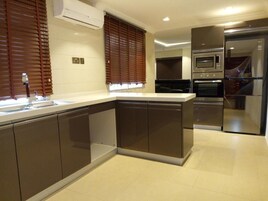 Uma cozinha moderna com armários escuros, uma ilha central e eletrodomésticos embutidos, incluindo micro-ondas e forno.