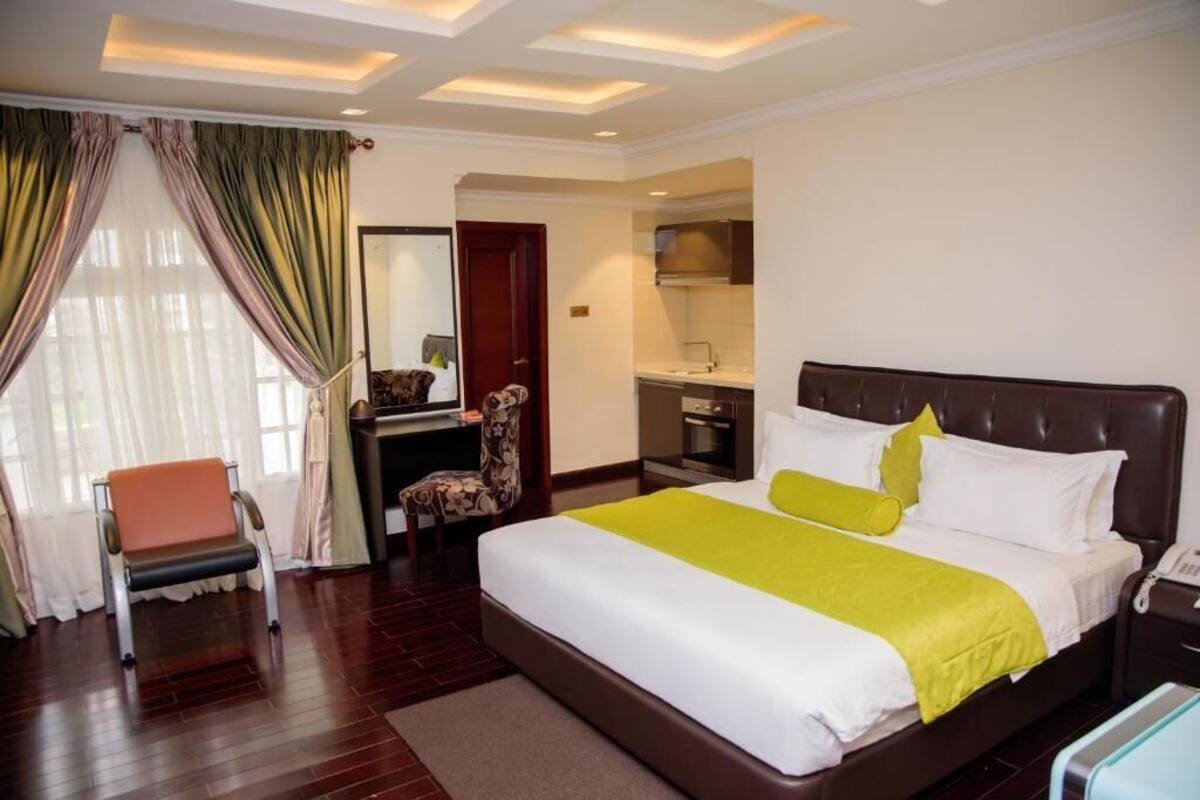 Habitación de hotel con una cama grande, un escritorio con silla, un baño y vistas al exterior.