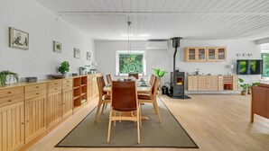 Un'ampia zona giorno con tavolo da pranzo, sedie, camino, pensili in legno e televisione.
