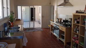 A kitchen with a stove, oven, and sink. There is a window with a view of the outside.