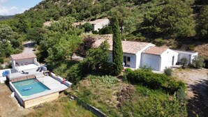 A residential property with a swimming pool, a patio, and a hillside backdrop.