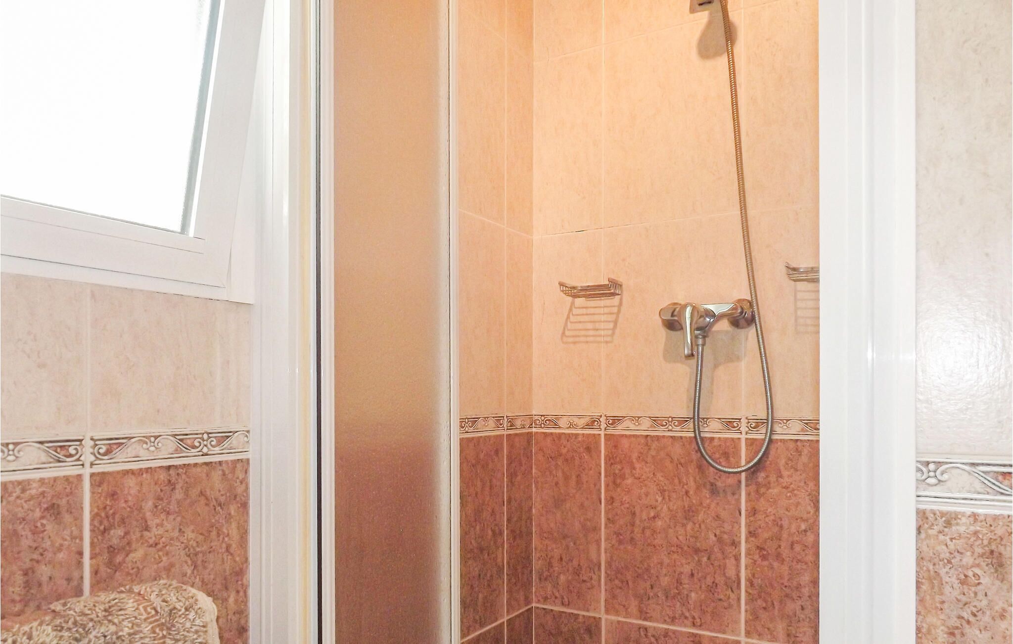 A shower with a handheld showerhead and a wall-mounted faucet.