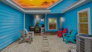 Un patio techado al aire libre con paredes azules, un camino de grava y mobiliario exterior.