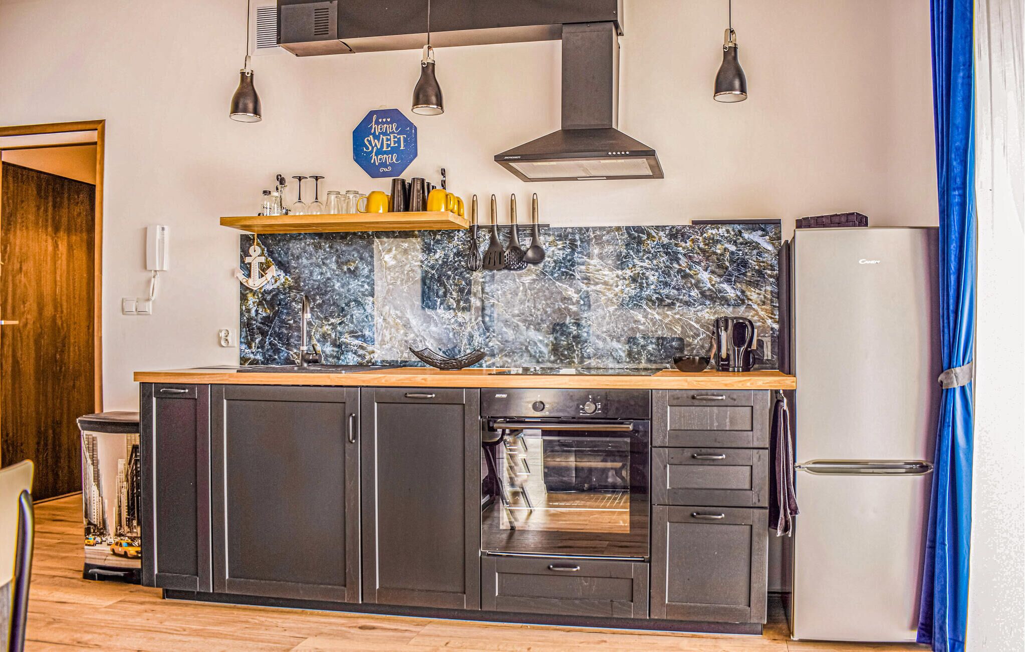 A kitchen with dark cabinets, a built-in oven, and a refrigerator.