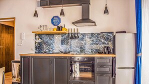 Una cocina con armarios oscuros, horno empotrado y refrigerador.