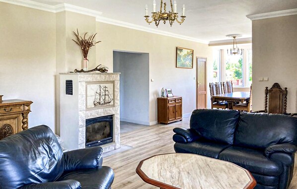 Cozy living room with a fireplace, leather sofa, and dining area.