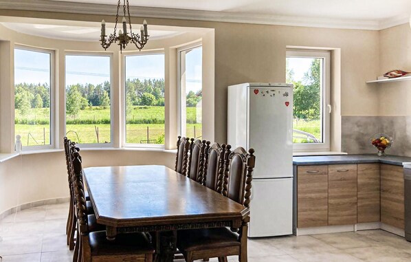Enjoy meals at the large dining table in this well-equipped kitchen with a refrigerator and cabinets.