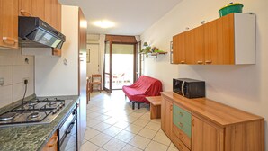 Eine Küche mit Gaskochfeld, Mikrowelle und Holzausstattung. Ein Stuhl mit roter Sitzfläche und ein kleiner Tisch sind ebenfalls vorhanden.