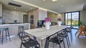 Una cucina moderna con elettrodomestici integrati, una zona pranzo con tavolo in marmo e un'ampia finestra che offre vista sull'esterno.