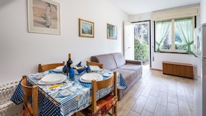 Un coin repas avec une table dressée pour deux personnes, un canapé et une fenêtre avec des rideaux.