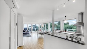A modern kitchen with a large island, stainless steel appliances, and a view of the outdoors. - Beautiful home in Strøby with house sea view (Strøby)