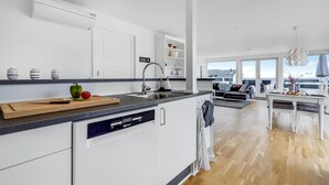 A modern kitchen with a dishwasher, a dining area with a view, and a living room with a sofa and a table. - Beautiful home in Strøby with house sea view (Strøby)