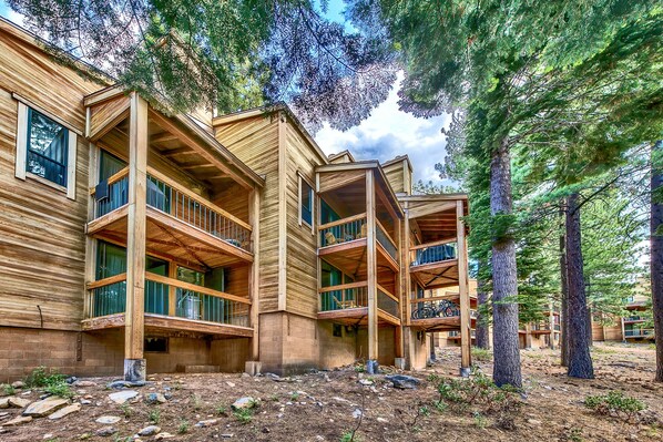 A multi-story wooden building with balconies, surrounded by trees.