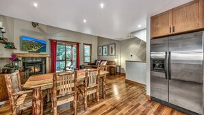 A spacious kitchen with a large stainless steel refrigerator, wooden dining table, and chairs.