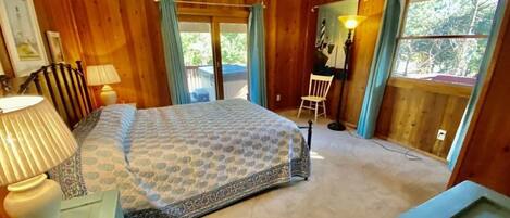 A wooden room with a bed, a desk, and a chair.