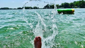 Voet in het water, met een groen voorwerp op de achtergrond.