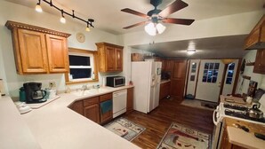 A kitchen with wooden cabinets, a white refrigerator, a microwave, a stove, and a ceiling fan.