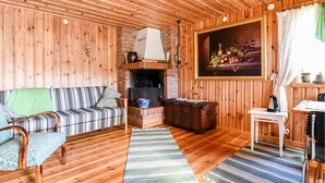 A cozy wooden room with a sofa, a fireplace, a painting, and a small table. - 1 bedroom awesome home in åmotfors (Åmotfors)