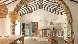A rustic kitchen with a wooden table, chairs, and a hanging light fixture.