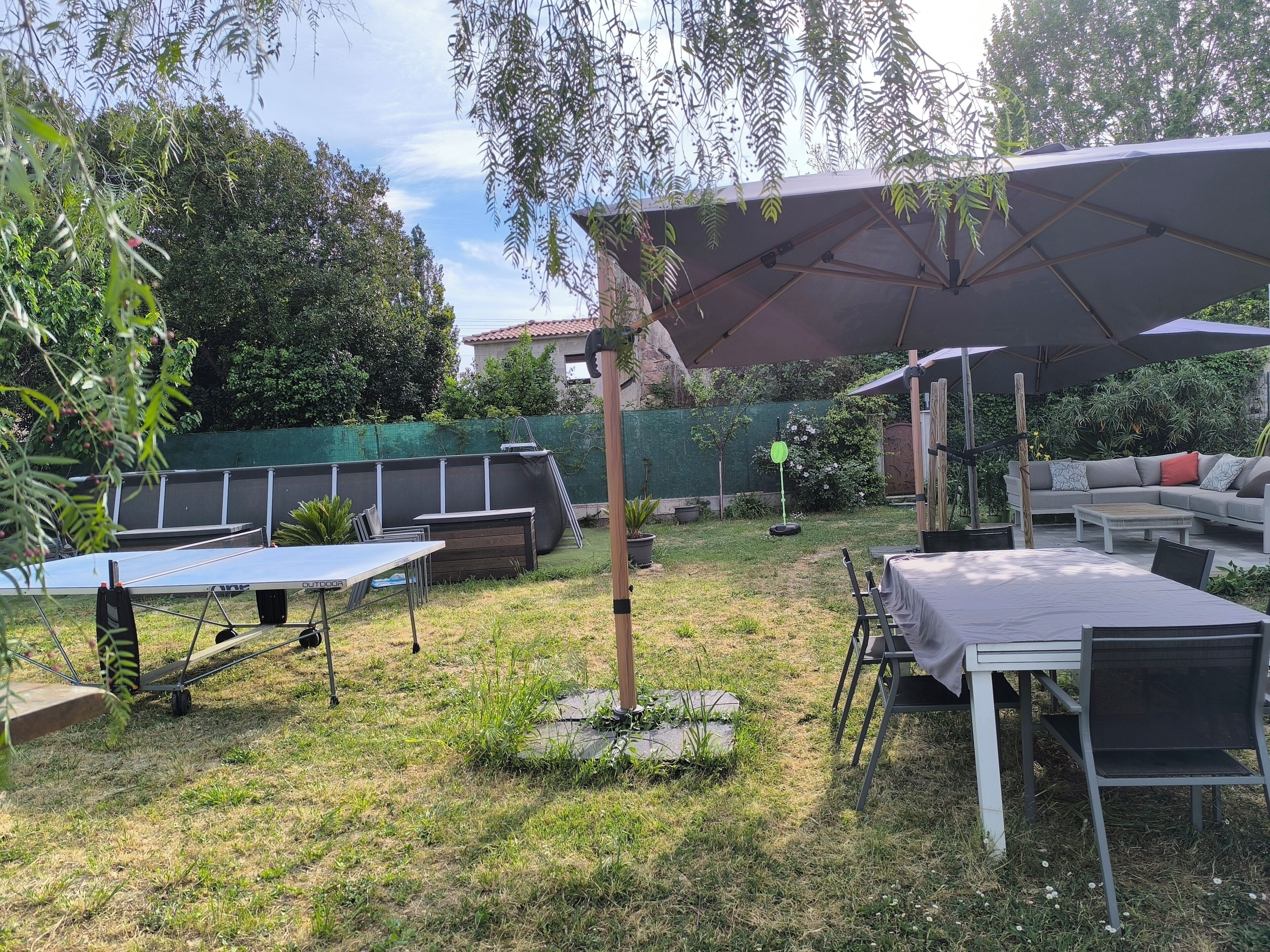 An outdoor patio area with a table, chairs, a sofa, and a large umbrella.