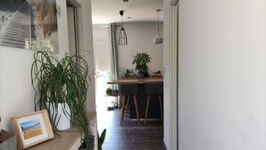 A hallway with a wooden bench, a framed picture, and a potted plant.
