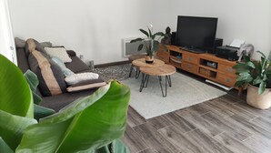 A living room with a sofa, a coffee table, a TV, and a wooden cabinet.
