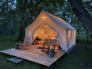 A cozy tent with a wooden deck, two chairs, a table, and a small fireplace. - Pony, MT — DOGS & HORSES OK — On private creek (Pony)