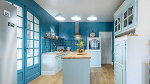 A kitchen with blue walls, white cabinets, and a wooden countertop. There are three pendant lights, a stove, and a sink. - Stunning home in Laurens (Laurens)