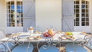 A table set for a meal with a white tablecloth, metal chairs, and a basket of bread. - Stunning home in Laurens (Laurens)
