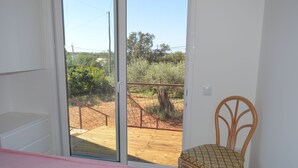 A bedroom with a sliding glass door leading to a wooden deck. - Casa Modular T2 (Quelfes)