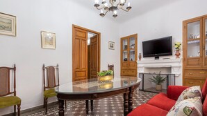 Ein Wohnzimmer mit Glastisch, rotem Sofa, Fernseher und Kamin.