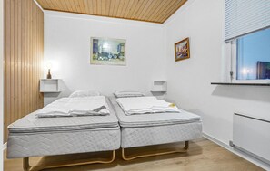 A room with two beds, a wooden ceiling, a window with blinds, and two wall-mounted lamps. - 4 bedroom lovely home in Knebel (Knebel)