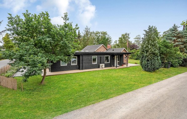 A small, single-story house with a dark exterior, a front porch, and a brick chimney. - 4 bedroom lovely home in Knebel (Knebel)