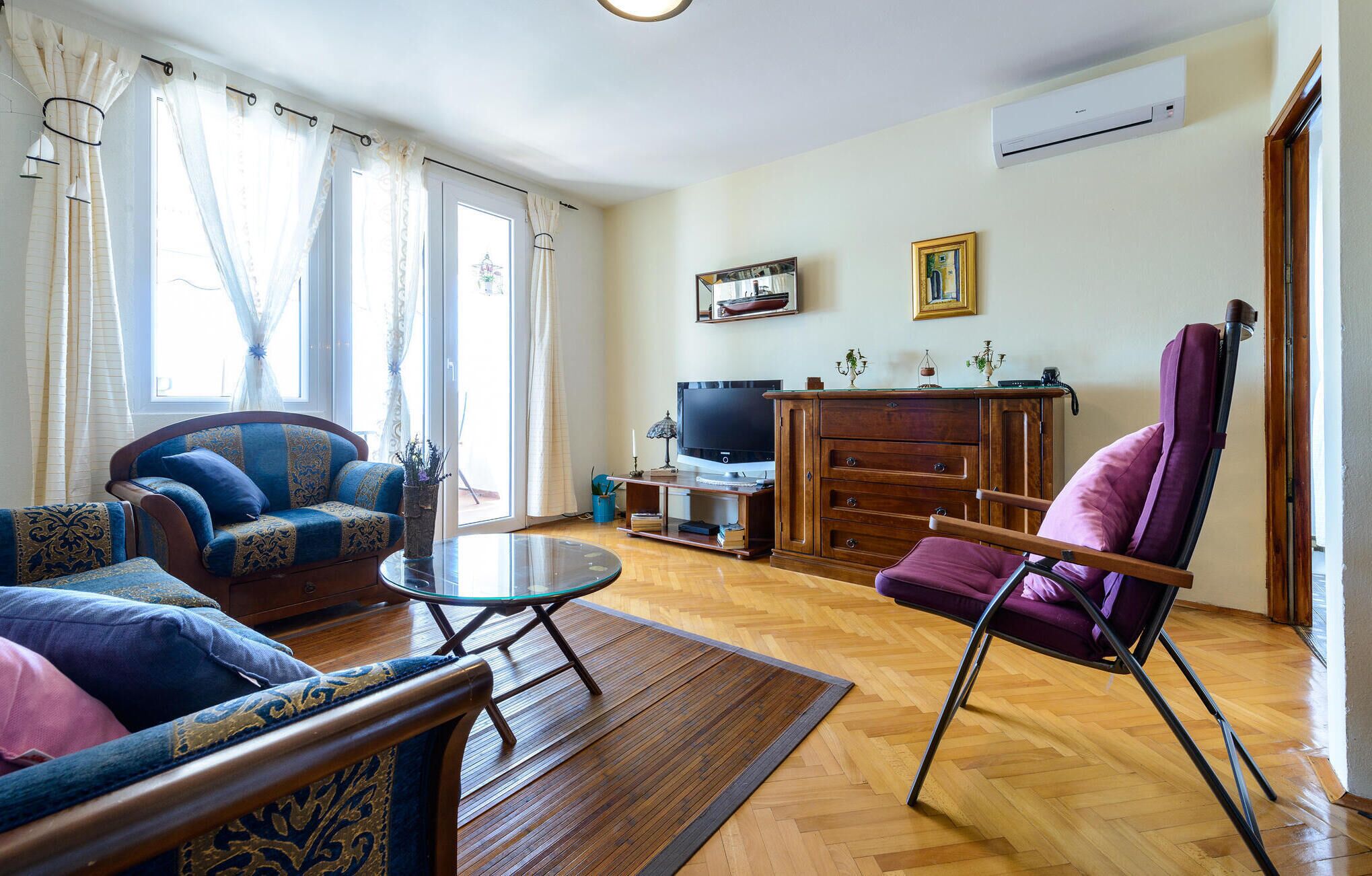 Un salon avec un canapé, un fauteuil et un meuble pour la télévision.