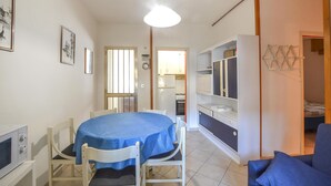 A compact living space with a dining area, kitchenette, and a TV. - Beach front apartment in Rosolina Mare (Rosolina Mare)
