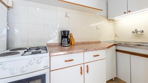 A kitchen with white cabinets, a gas stove, a coffee maker, and a sink. - 1 bedroom stunning apartment in Pisak (Pisak)