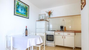 A small kitchen with a dining table, chairs, a refrigerator, an oven, and a coffee maker. - 1 bedroom stunning apartment in Pisak (Pisak)
